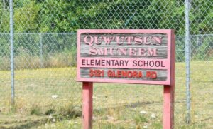 Rotes Holzschild vor Zaun: ‚Quw’utsun Smuneem Elementary School – 3121 Glenora Rd‘, Grundschule der Cowichan First Nation.
